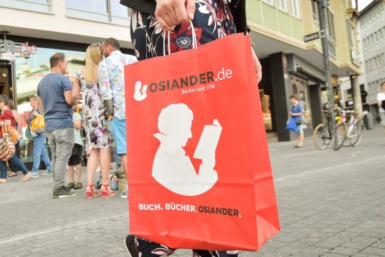 Kunde trägt Osiander Papirtüte vor Filiale in Stuttgart